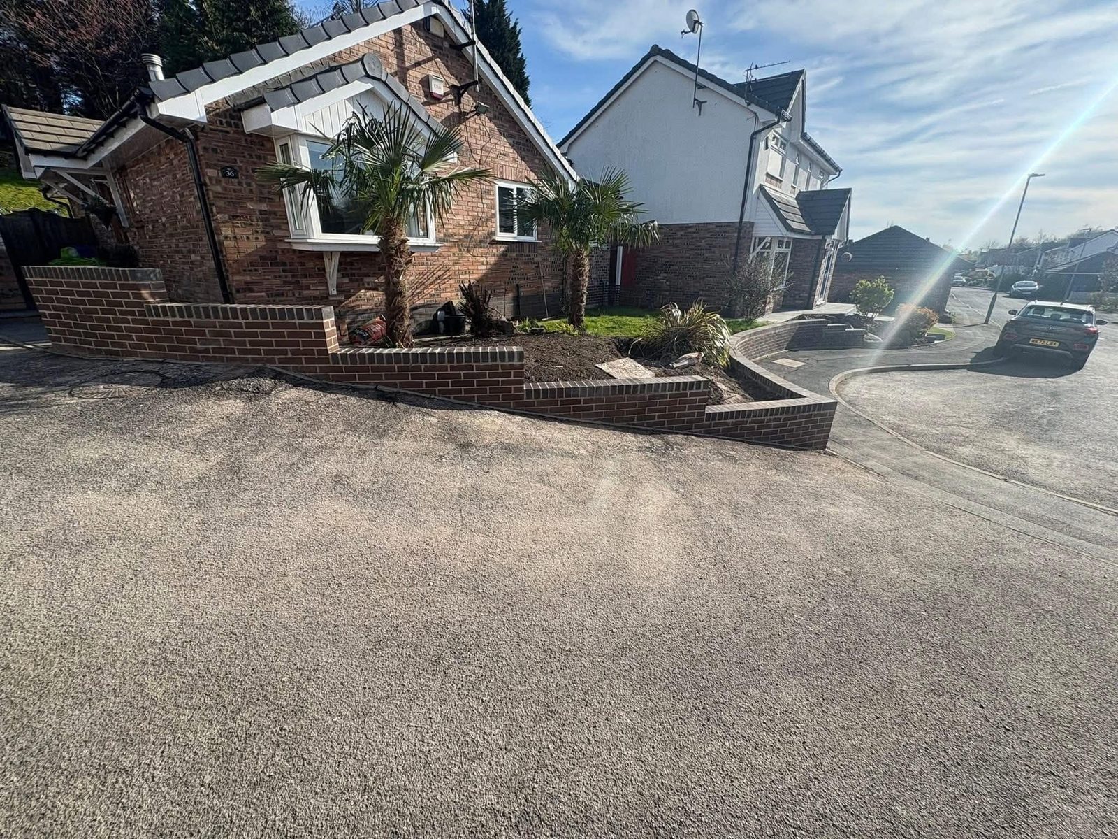Completed brick retaining wall and planters alongside a resurfaced driveway